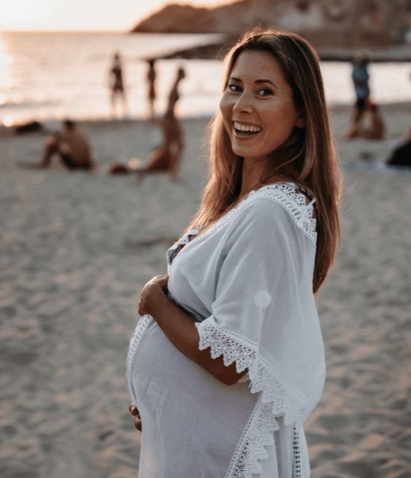 Nadya Andreeva, pregnant, smiling on a beach at sunset